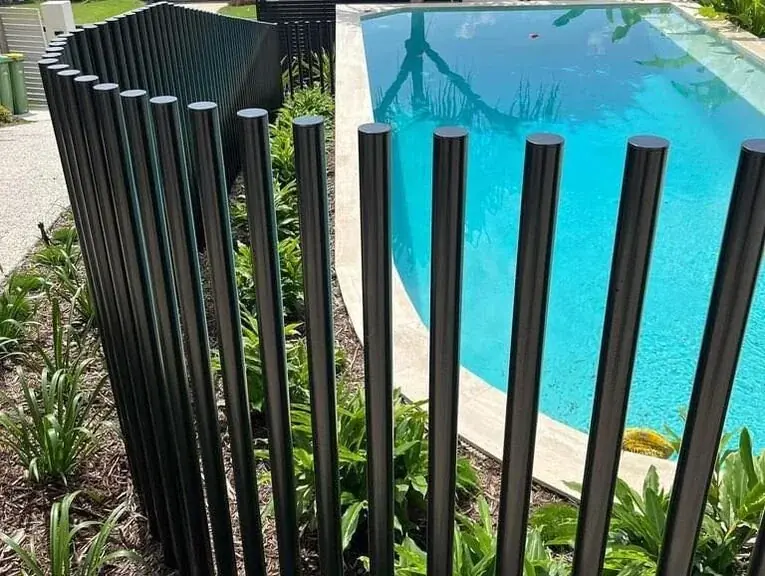 Architectural black aluminium batten pool safety barrier around a landscaped residential swimming pool.
