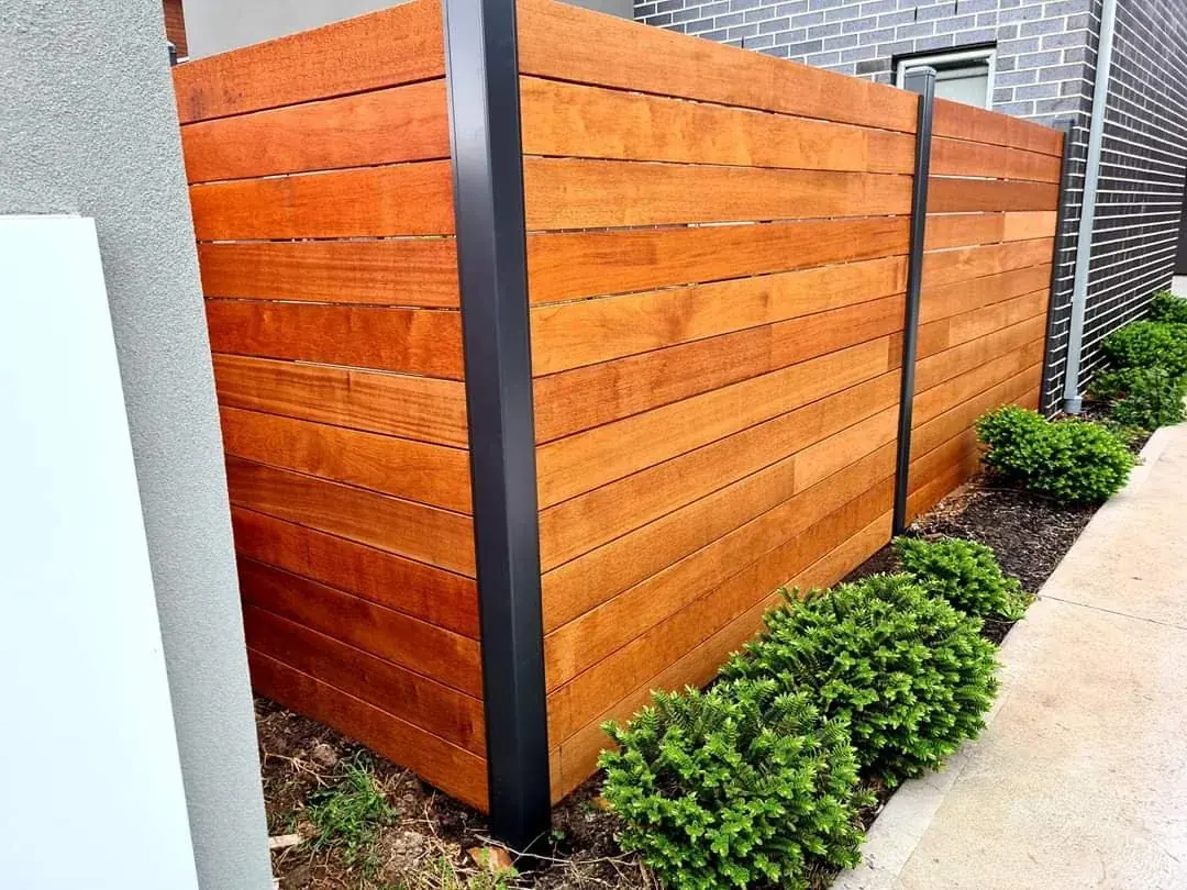 Premium horizontal treated timber boundary fence featuring clean lines and sturdy black steel structural posts installed between two Melbourne residential properties.